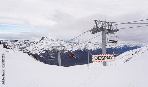 View of a ski slope with some warning signs and a chairlift on Castor ski center, on a cloudy winter day, with a mountain range on the background. Ushuaia, Tierra del Fuego, Argentina © AgusCami