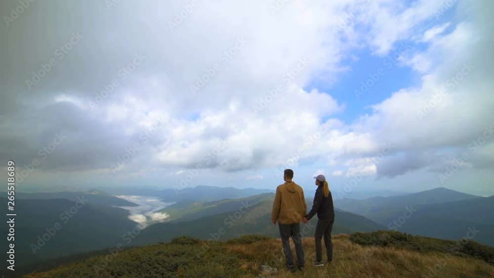 The couple hugs on the mountain with a picturesque landscape view The couple hugs on the mountain with a picturesque landscape view