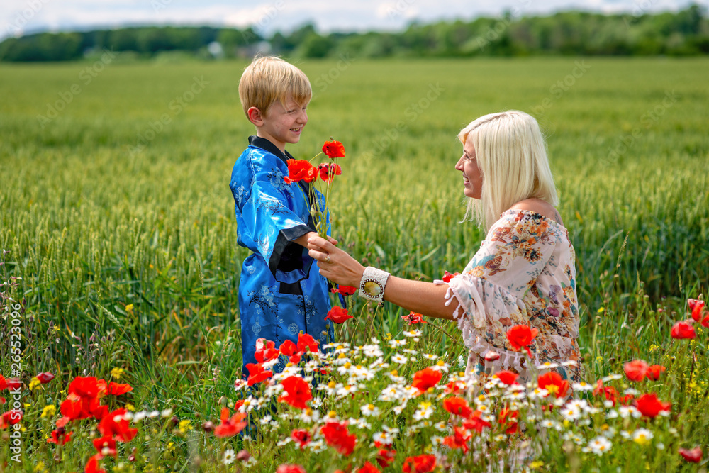 Mom with her son in a magnificent meadow. The boy surprised her mother with red poppies. Mom with her son in a magnificent meadow. The boy surprised her mother with red poppies.