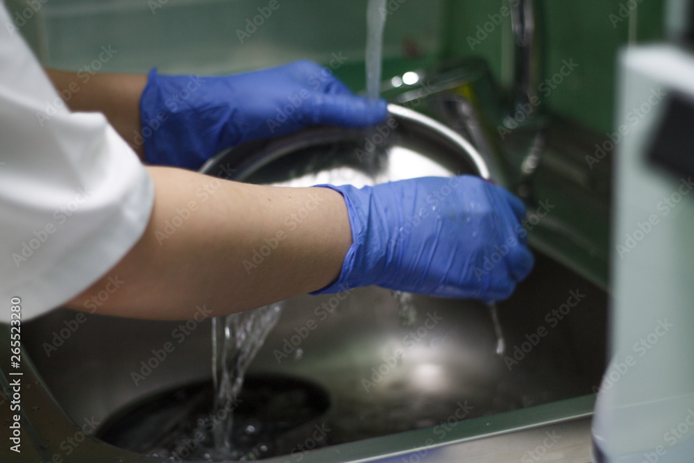 washing dental instruments with blue gloves close-up water