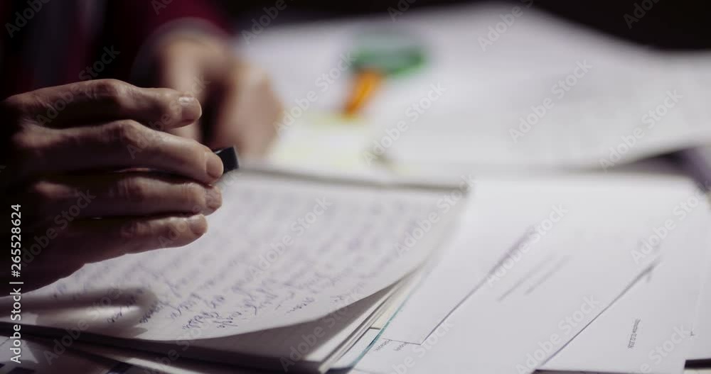 Closeup of businessman writing on paper at table in office Closeup of businessman writing on paper at table in office