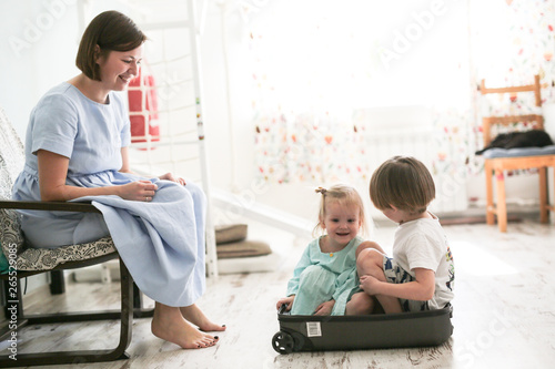 Children are sitting in suitcase near mother