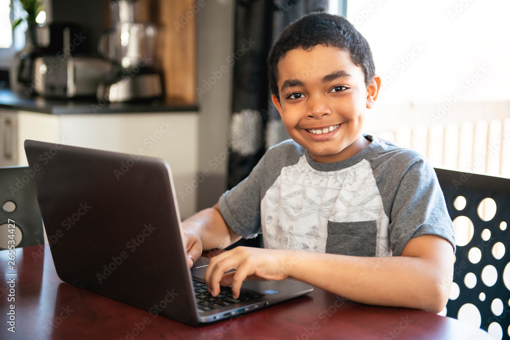 Black boy sitting playing on a laptop computer at home Black boy sitting playing on a laptop computer at home