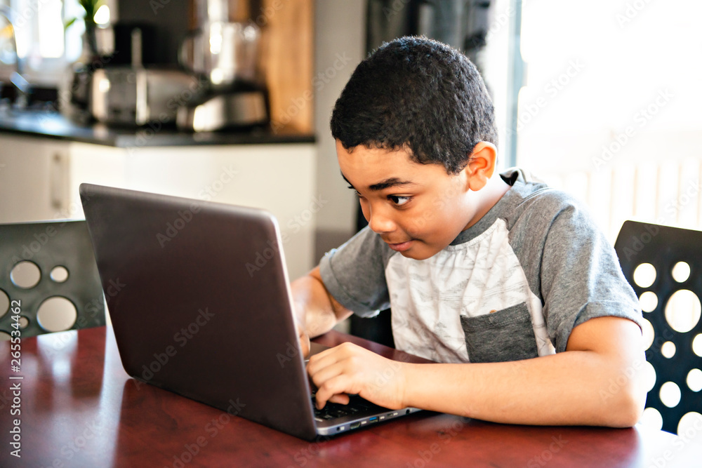Black boy sitting playing on a laptop computer at home Black boy sitting playing on a laptop computer at home