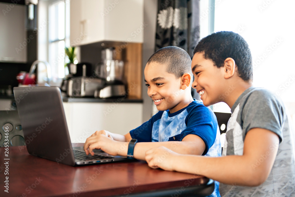 two Black boy sitting playing on a laptop computer at home two Black boy sitting playing on a laptop computer at home