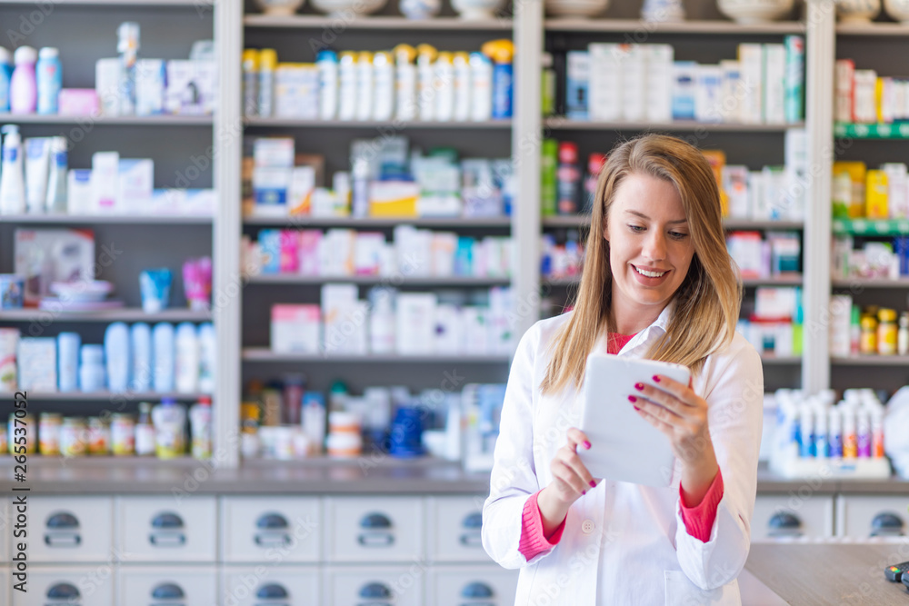Portrait of pharmacist holding digital tablet in pharmacy. Pharmacist working with a tablet-pc in the pharmacy holding it in her hand while reading information
