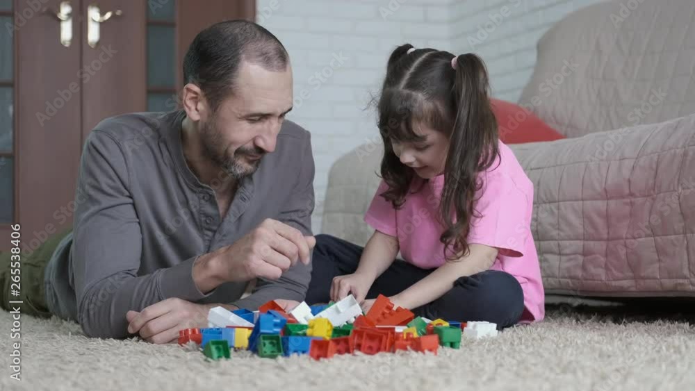 Father with daughter. Little girl with dad assembles the constructor. Father with daughter. Little girl with dad assembles the constructor.
