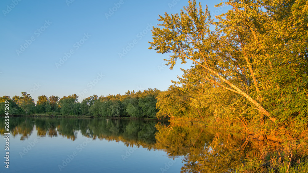 Beautiful sunny late summer day at dusk on the St. Croix River - reflection of trees on calm river waters