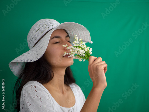Jeune fille au chapeau qui sent du muguet le 1er mai