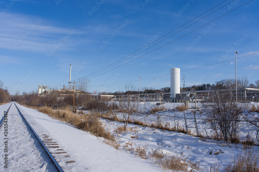 Snowy straight railroad track - industrial business with equipment off the tracks - near the Minnesota River and near coal power plant Snowy straight railroad track - industrial business with equipment off the tracks - near the Minnesota River and near coal power plant