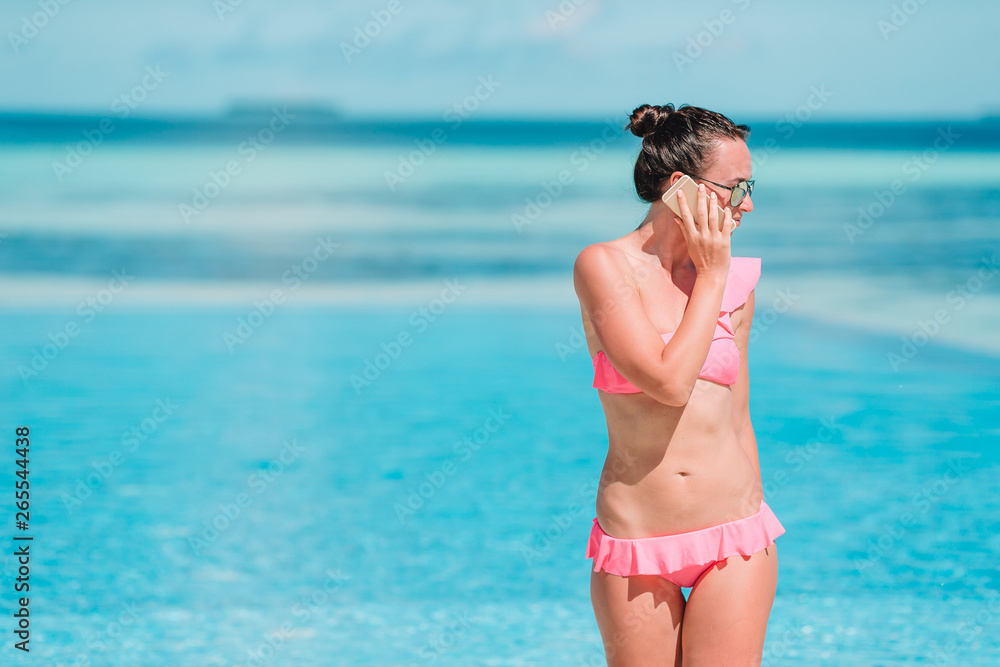 Young beautiful woman talking by phone on white beach