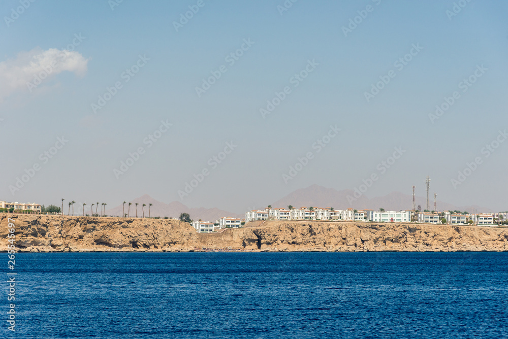 Naklejka premium hotels and houses in the distance stand over a cliff above the blue sea.