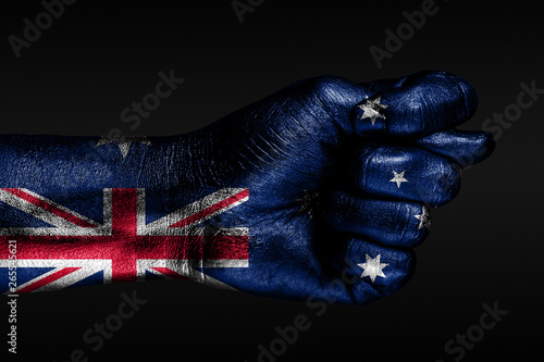 A hand with a painted Australia flag shows a fig, a sign of aggression, disagreement, a dispute on a dark background.