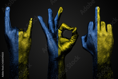 a set of three hands with a painted flag Ukraine show middle finger, goat and Okay, a sign of aggression, protest and approval on a dark background. photo