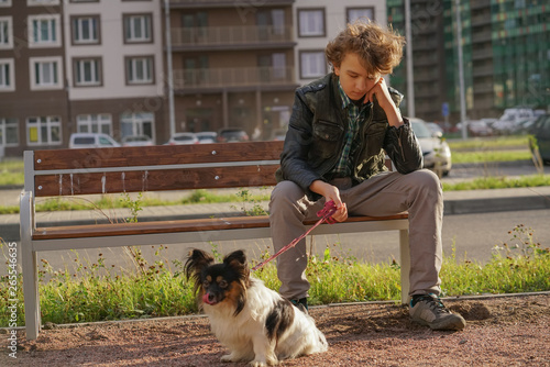 sad lonely guy sitting on a bench with his dog. the difficulties of adolescence in communication concept. photo