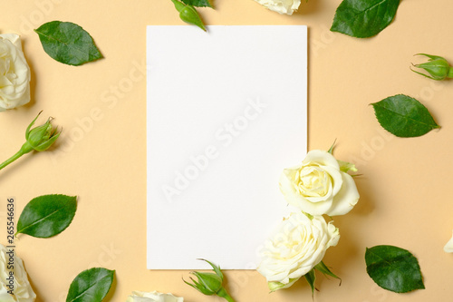 Spring flowers. White flowers and green leaves on pastel yellow background. Flat lay, top view, copy space. Creative layout, flower arrangement concept.