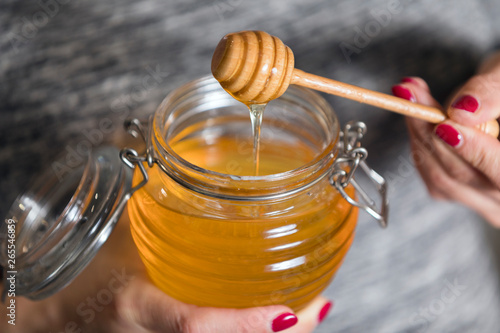 Woman hand holding glass jar of honey