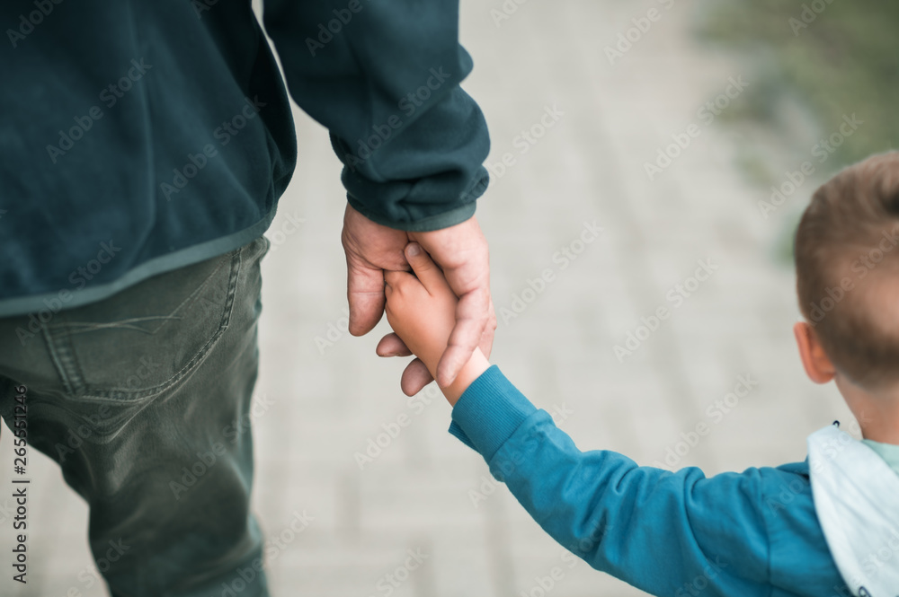 Little boy walking together with his father