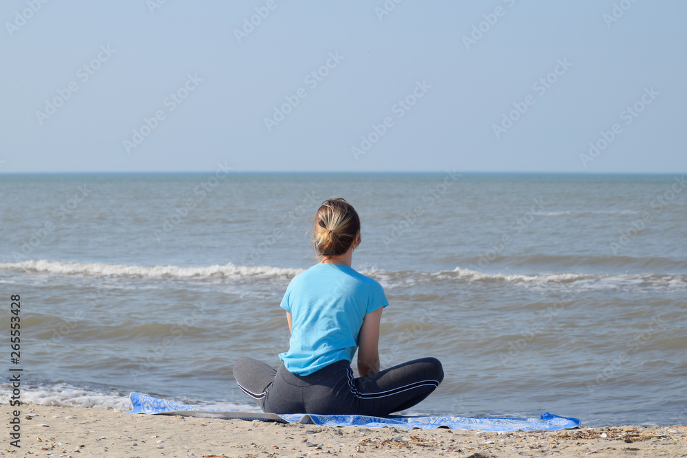 girl practices yoga by the sea. Exercise gymnastics in the fresh air by the sea.