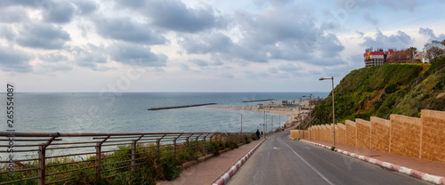 Panoramic view of a scenic road leading to a sandy beach during a cloudy day. Taken in Netanya, Center District, Israel. photo