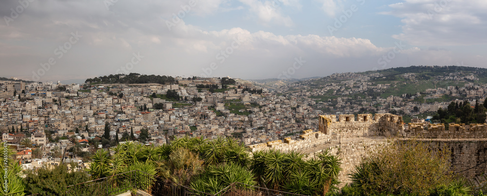 Beautiful panoramic view of the Walls of Jerusalem surrounding the Old City with the cityscape in the background during a cloudy day. Taken near the Jerusalem, Israel.