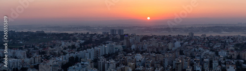 Aerial panoramic view of a residential neighborhood in a city during a vibrant and colorful sunrise. Taken in Netanya  Center District  Israel.