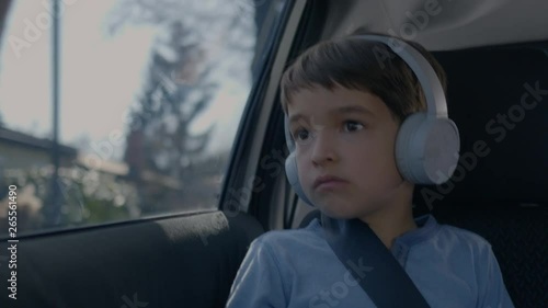 Boy driving and looking through a car window while listening to music photo