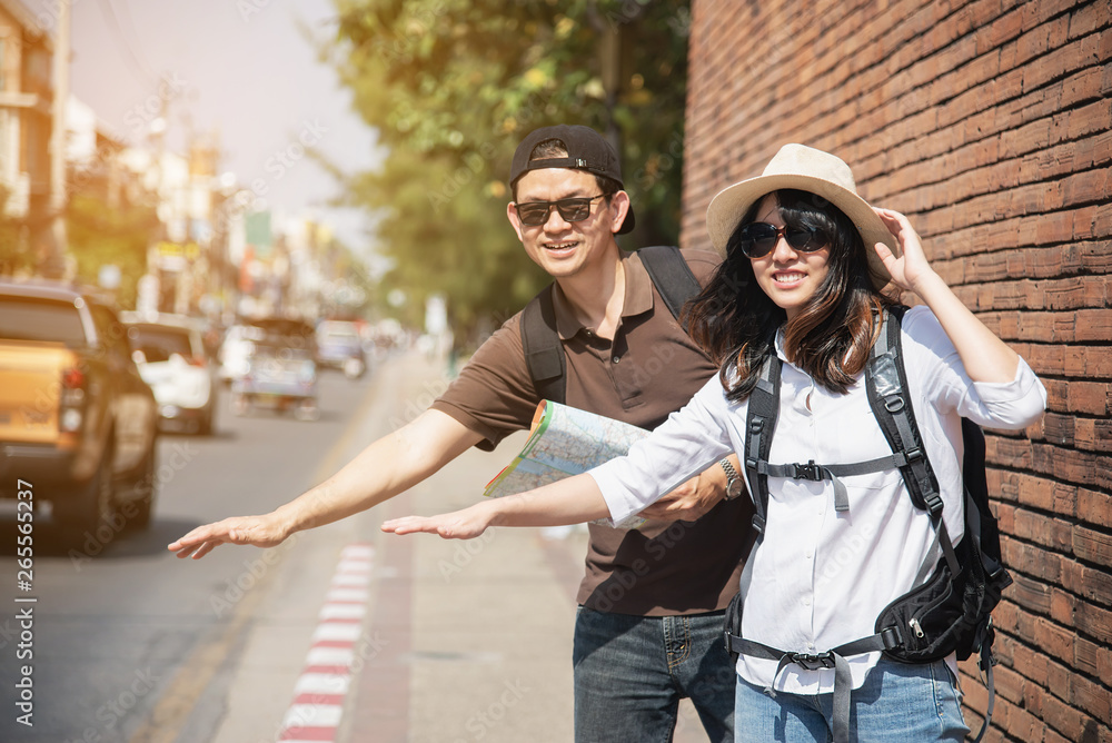 Asian backpack couple tourist holding city map crossing the road - travel people vacation lifestyle concept