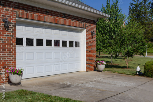 Generic house with double garage door, red brick and pots of flowers, horizontal aspect