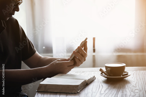 Man using mobile phone while drinking coffee and reading book in coffee shop - modern life style people in coffee shop concept