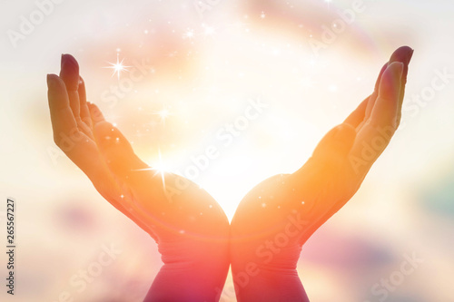 Silhouette of female hands holding sunset or sunrise for people energy and serene hope concept
