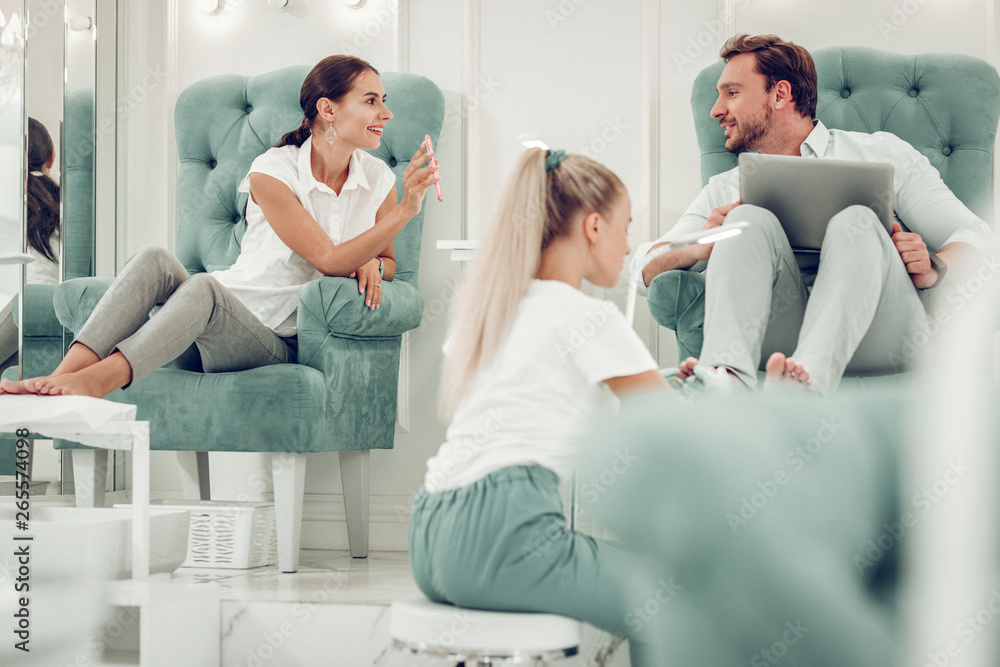 Active dark-haired woman showing smartphone screen to her curious husband Active dark-haired woman showing smartphone screen to her curious husband