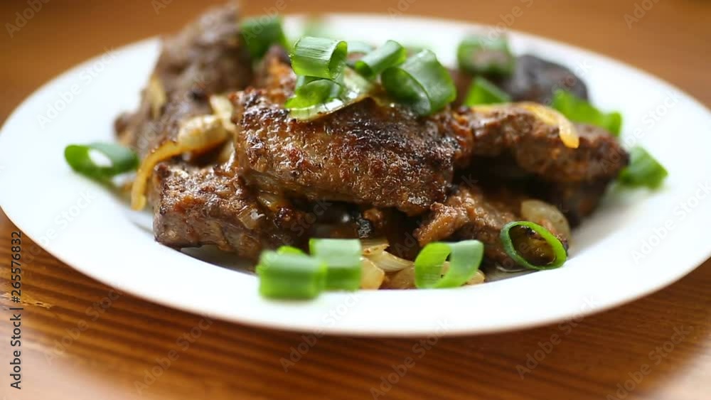 fried liver with onions in a plate on a wooden table fried liver with onions in a plate on a wooden table