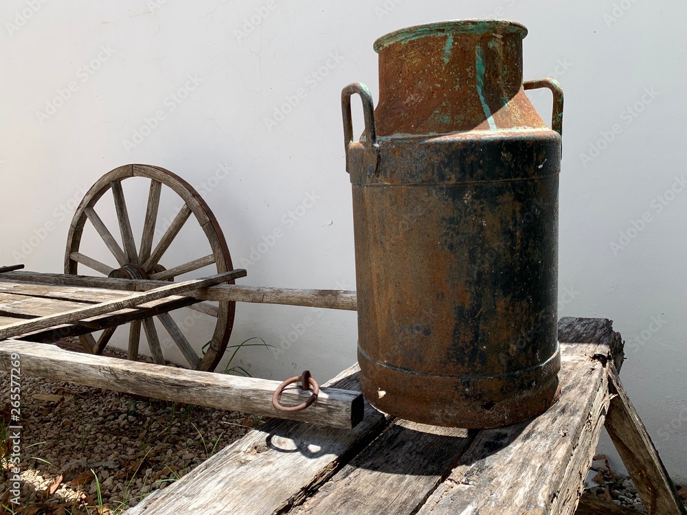 Carretilla antigua en madera para transportar mercancías y recipiente  lechero de metal. Stock Photo | Adobe Stock