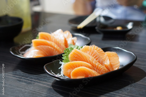 Salmon sashimi - Raw fresh salmon sliced served on black plate with wasabi and shredded radish, Traditional Japanese food.