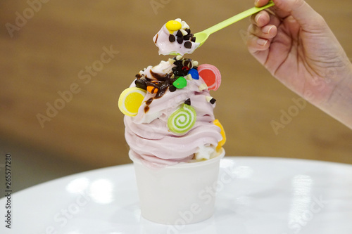 A plastic cup of organic frozen yogurt Ice cream topped with chocolate and jelly on blurred background.