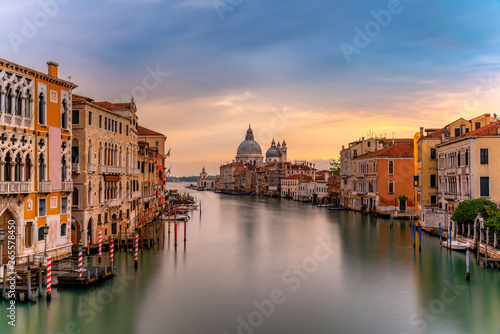 Beautiful landscape sunset view of traditional Gondolas on famous Canal Grande with historic Basilica di Santa Maria della Salute in the background in romantic golden evening light at sunset in Venice © martinhosmat083