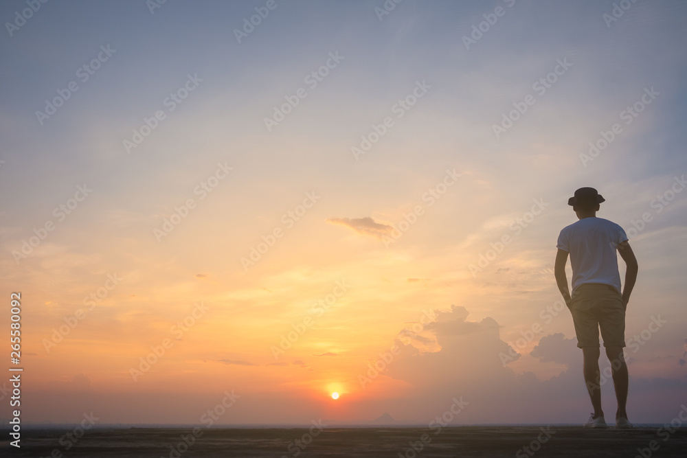 Traveler young man standing in the summer mountains at sunset and enjoying view of nature.