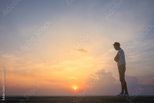 Traveler young man standing in the summer mountains at sunset and enjoying view of nature.