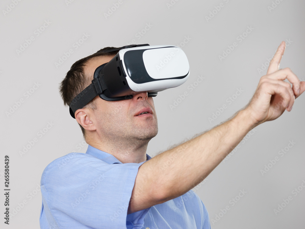 Man wearing virtual reality goggles on grey Man wearing virtual reality goggles on grey