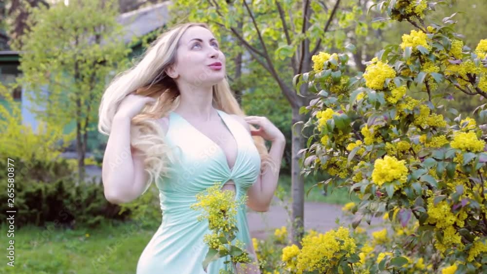 Young blond woman is enjoying herself in a flowered garden. Young blond woman is enjoying herself in a flowered garden.