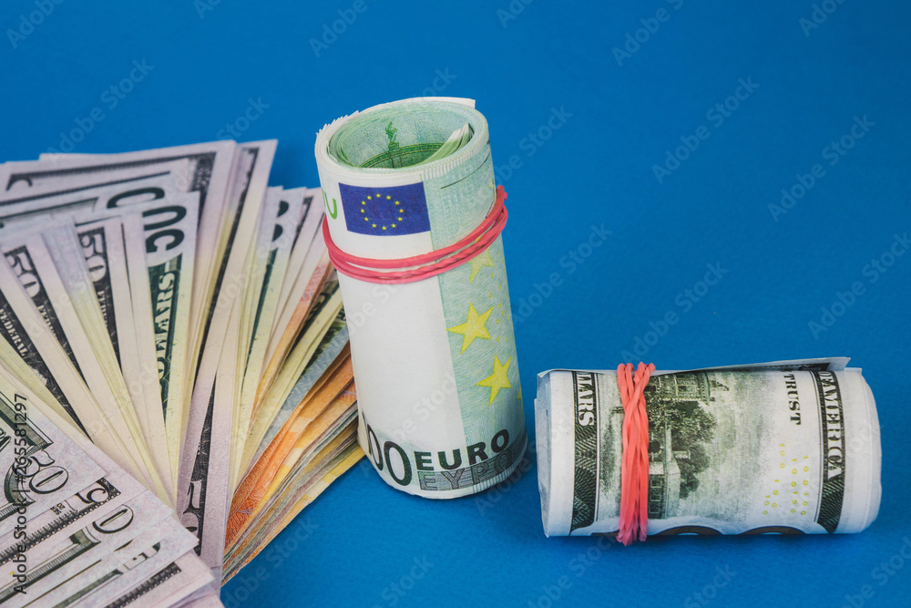 several wads of money of different currencies on a blue background. several wads of money of different currencies on a blue background.