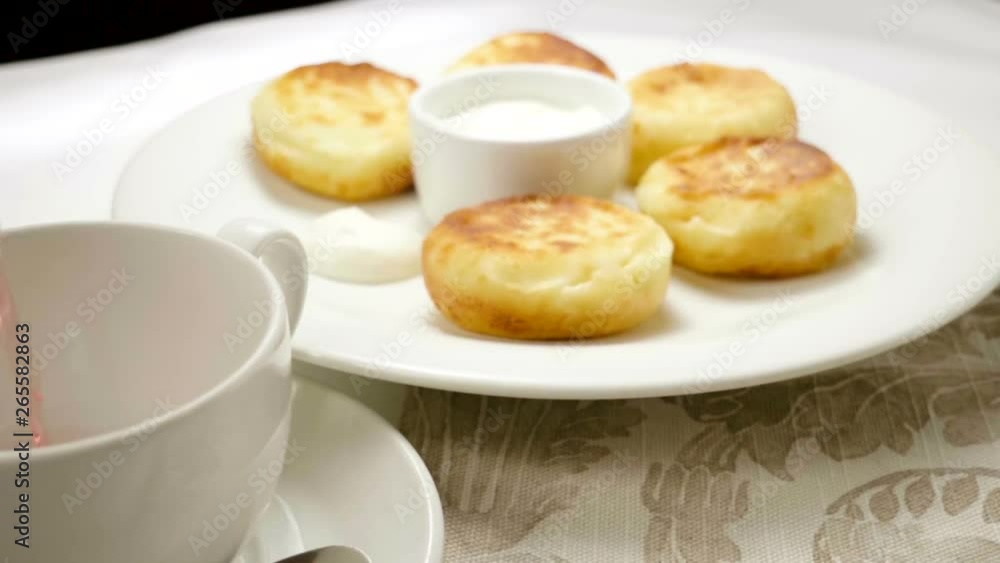 Fruit tea is being poured into a cup on the background of a plate with cheesecakes. Slow motion. HD Fruit tea is being poured into a cup on the background of a plate with cheesecakes. Slow motion. HD