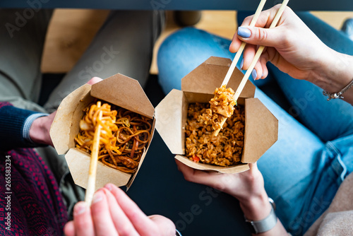 Vászonkép couple eating food packed in take-away box with chopsticks