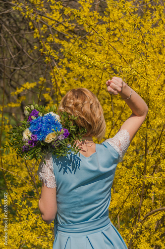Girl with a bouquet on the background of a yellow bush
