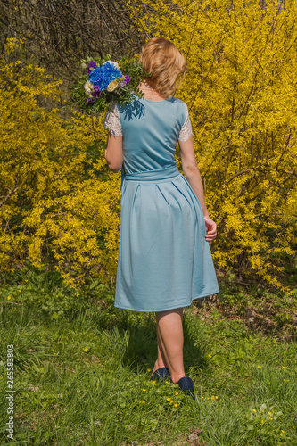 Girl with a bouquet on the background of a yellow bush