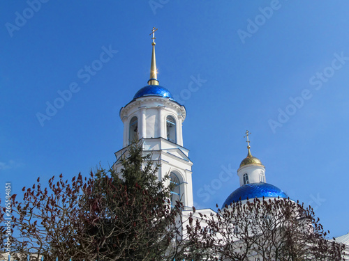 Sumy, Ukraine - April 1, 2019: Blue dome with a gold cross shining in the sun of Prophet-Ilyinsky temple in Sumy. Beautiful orthodox background with copy space, part of the church in classicism style photo