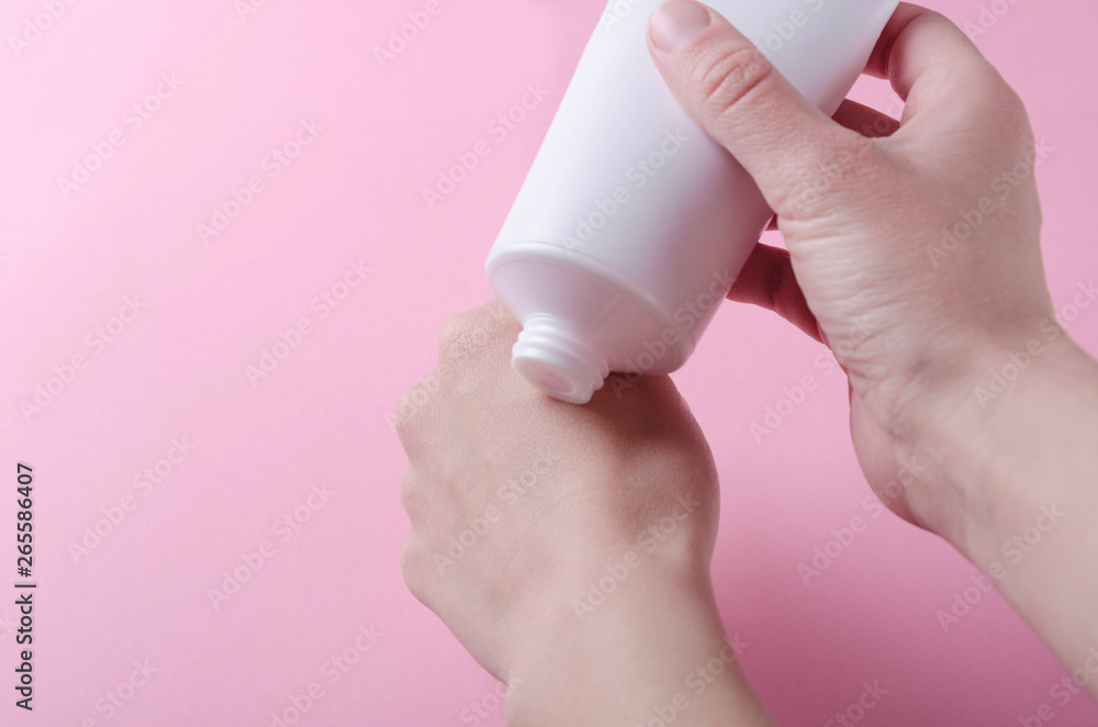 Closeup of woman`s hands and plastic tube with cosmetic cream.Woman squeezing moisturizing cream on her hands Closeup of woman`s hands and plastic tube with cosmetic cream.Woman squeezing moisturizing cream on her hands