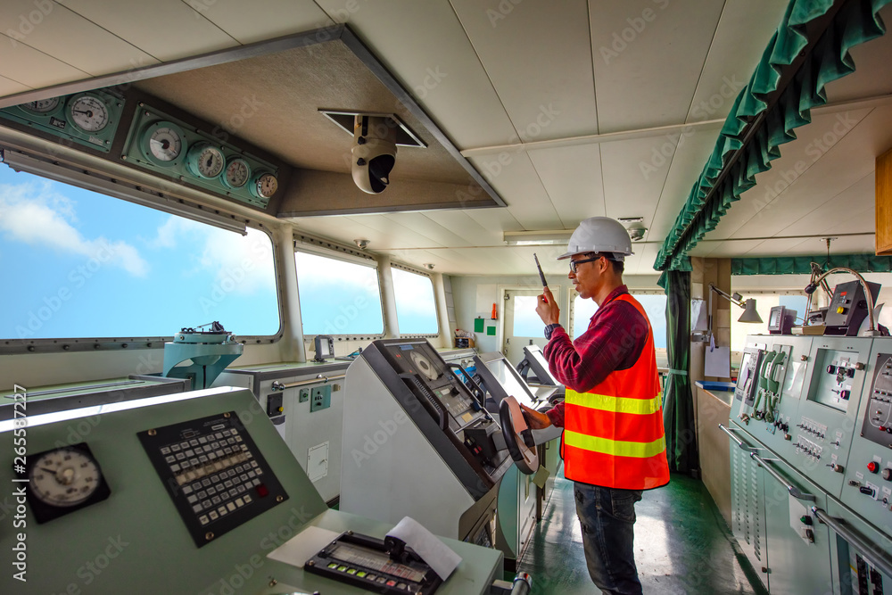 duty officer in charge handle of the ship navigating to the port destination, keep watching navigation on the bridge of the ship vessel under voyage sailing to the sea - obrazy, fototapety, plakaty 