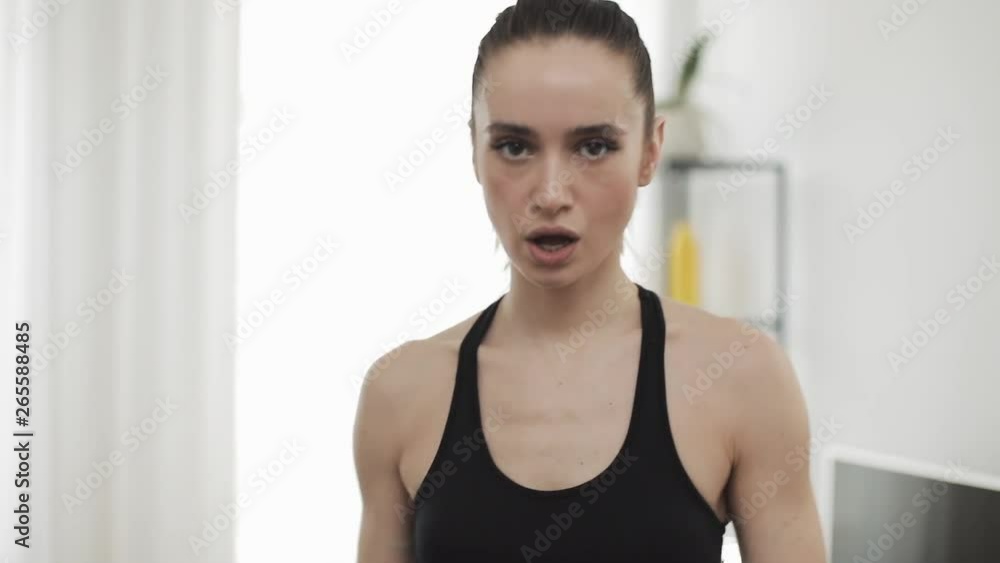 Portrait of young women after training at home. Fitness girl looking into the camera. Slow motion. Healthy and sport lifestyle.
